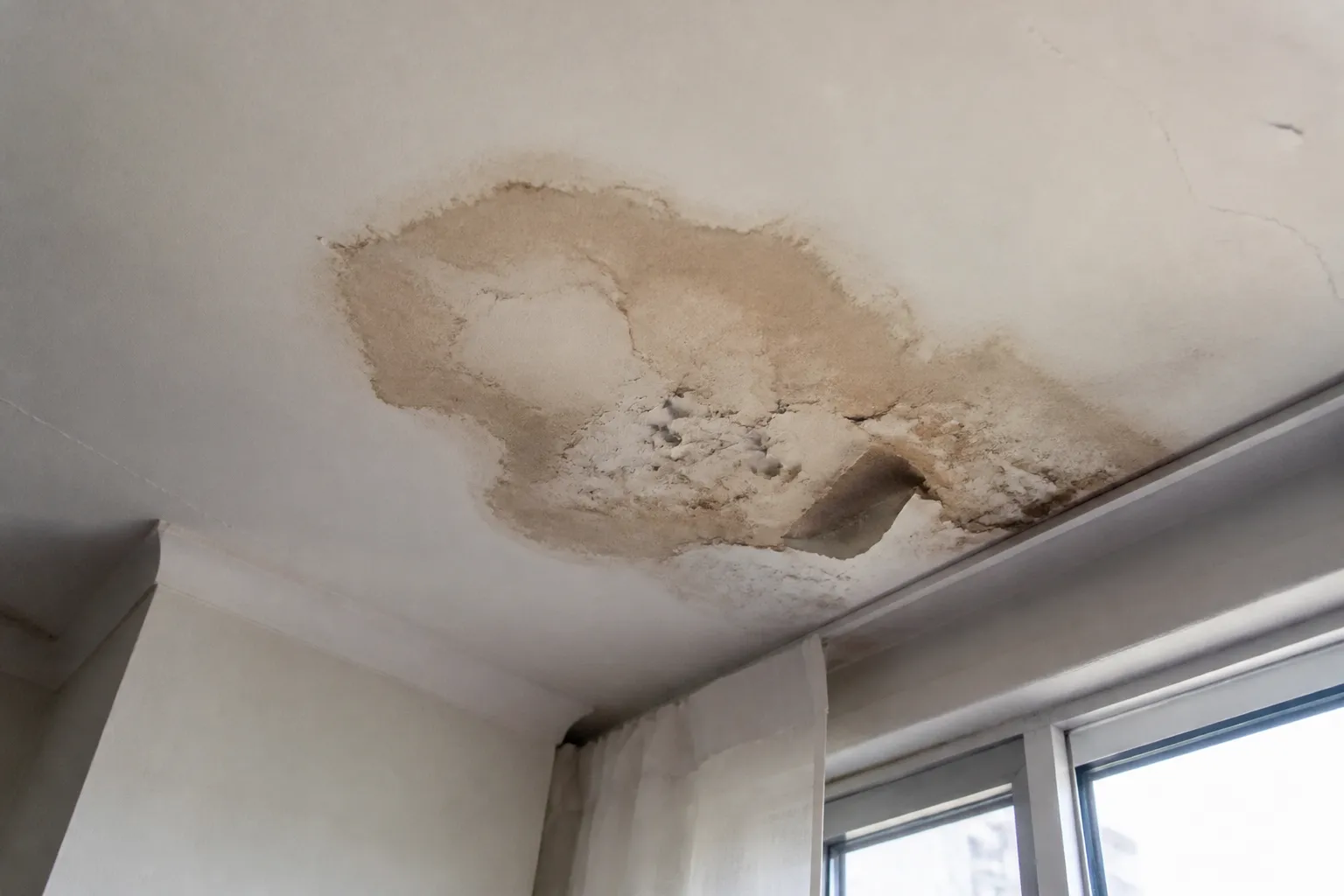 Tache d'infiltration au plafond d'un appartement sous toiture-terrasse