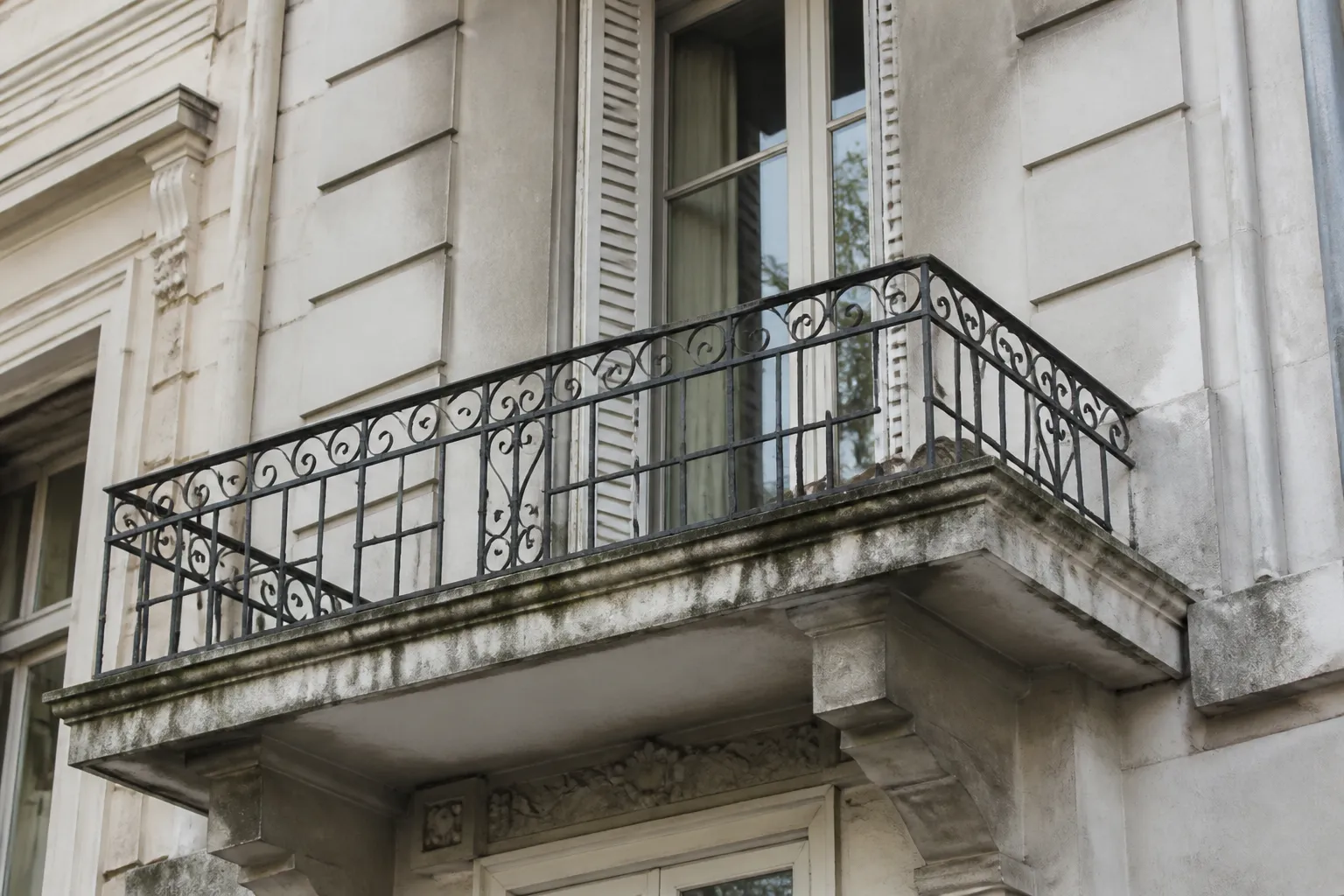 Balcon en béton ancien avec garde-corps ouvragé sur une façade