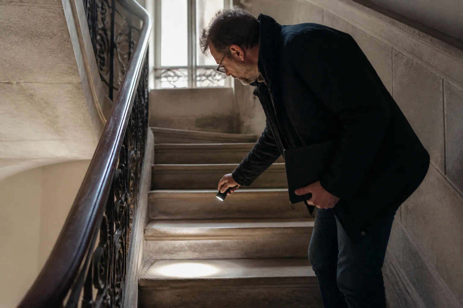 Expert en bâtiment inspectant une cage d’escalier d’immeuble ancien