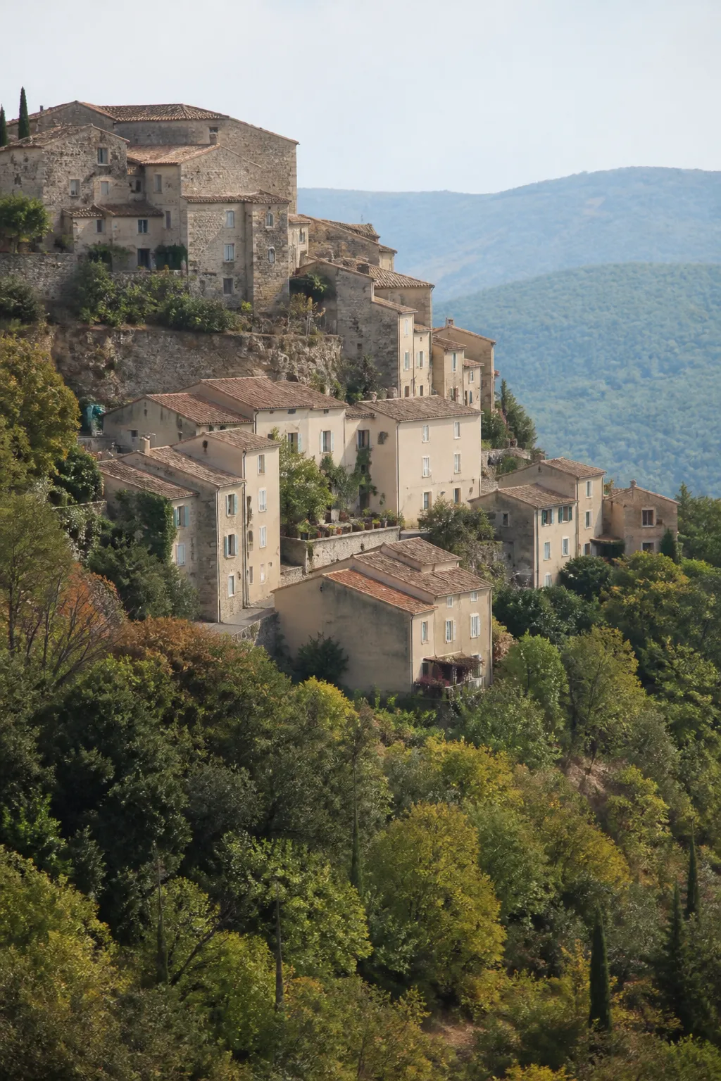 Maisons anciennes étagées sur une colline au-dessus d’une vallée boisée