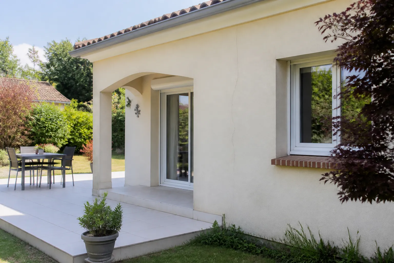 Pavillon avec dallage extérieur et fissure fine sur un mur enduit