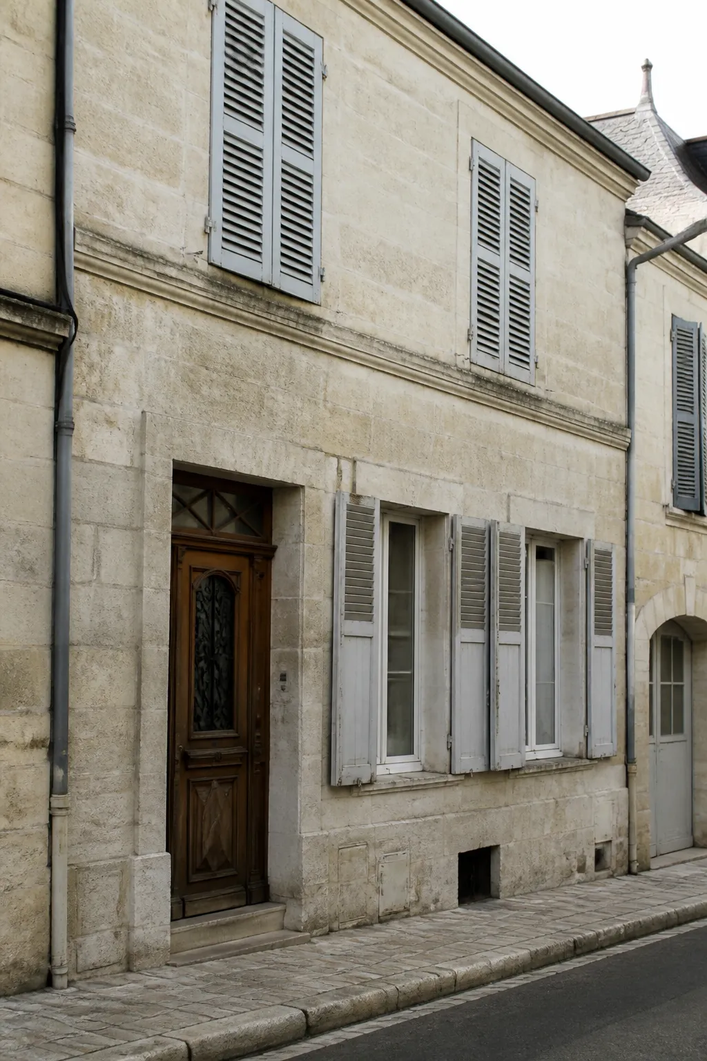 Maison de ville en pierre de taille claire avec volets en bois