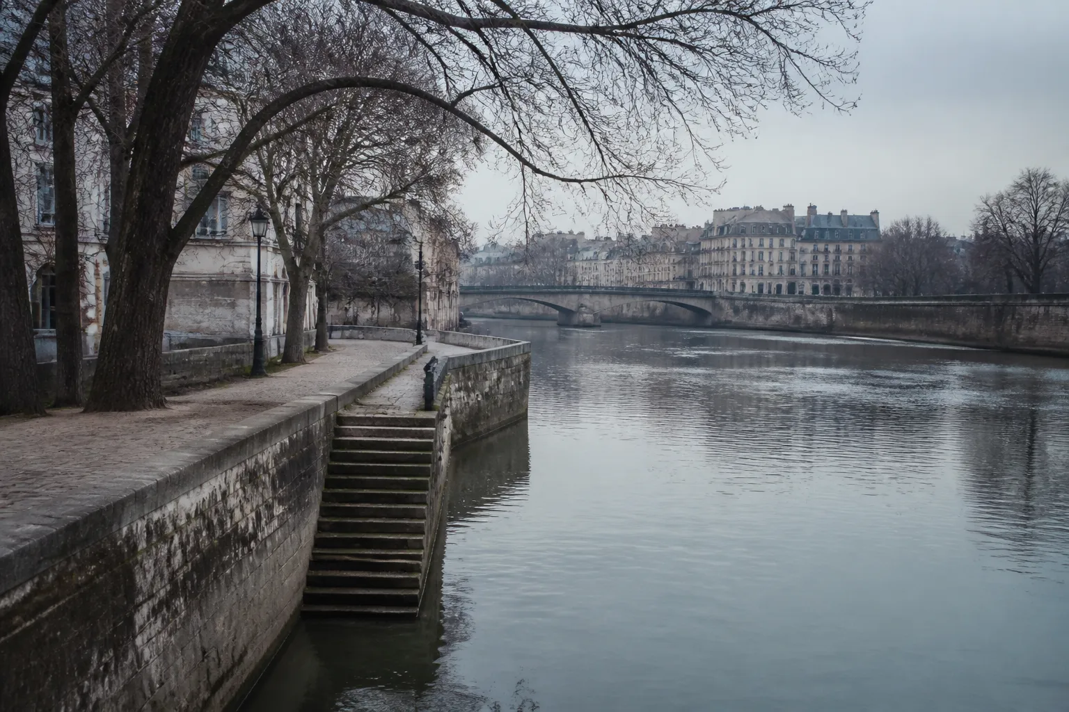 Quai en pierre au bord d’un fleuve calme en hiver