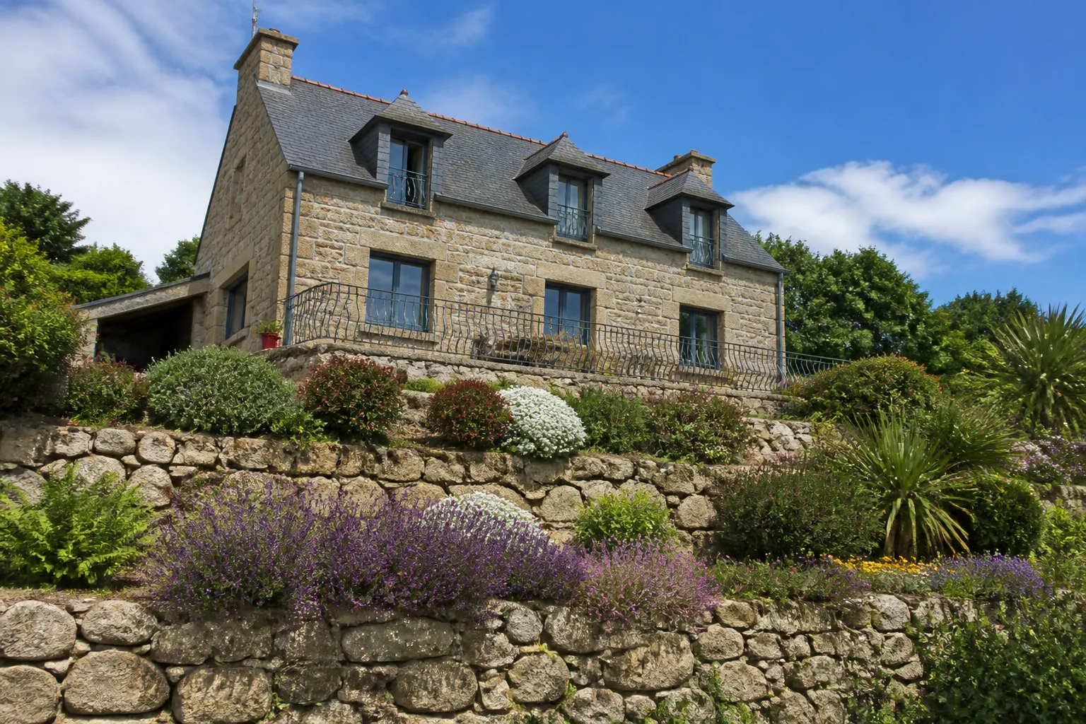 Maison sur terrain en pente avec mur de soutènement en pierre