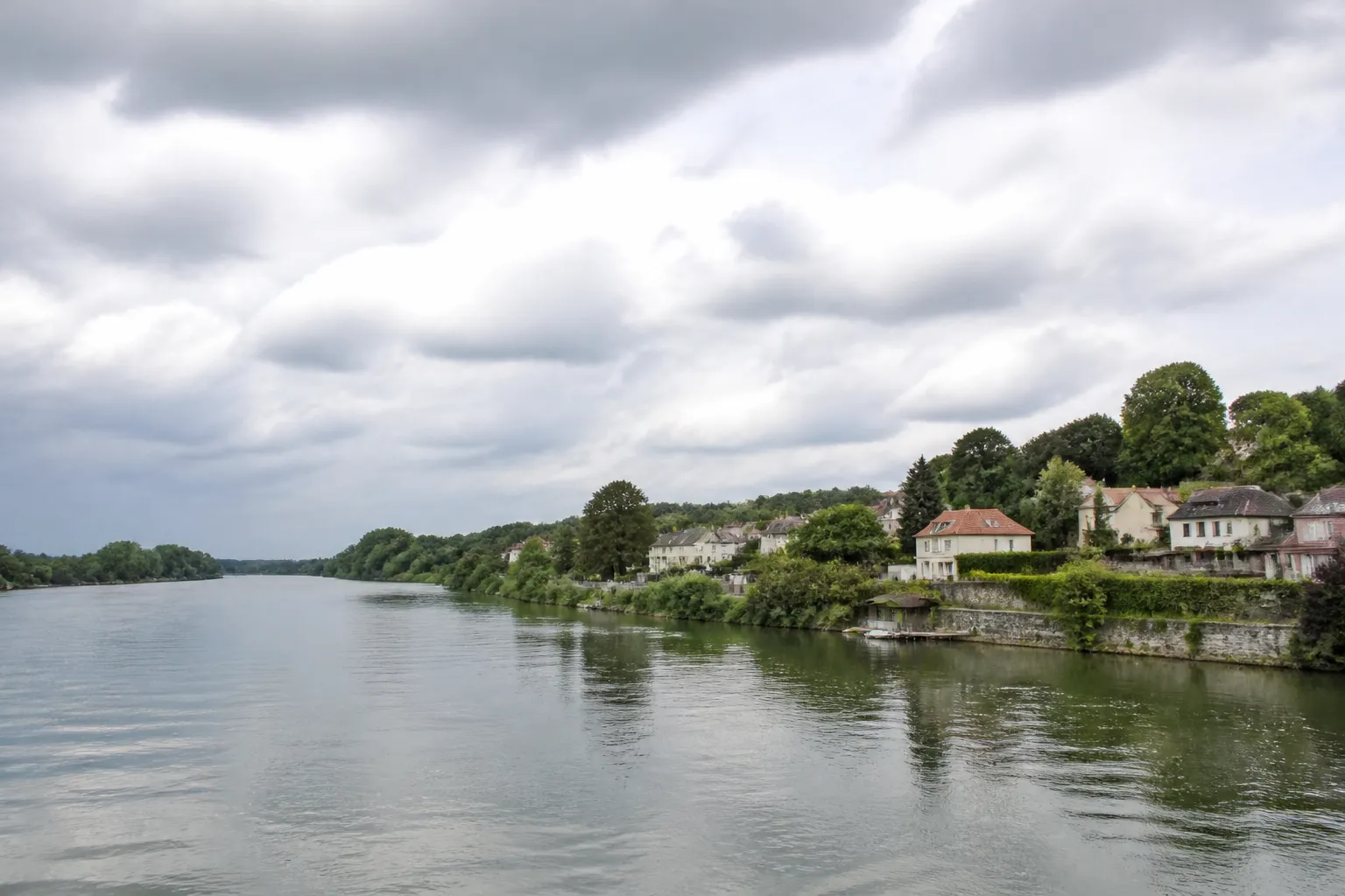 Berges d’un grand fleuve avec maisons et arbres