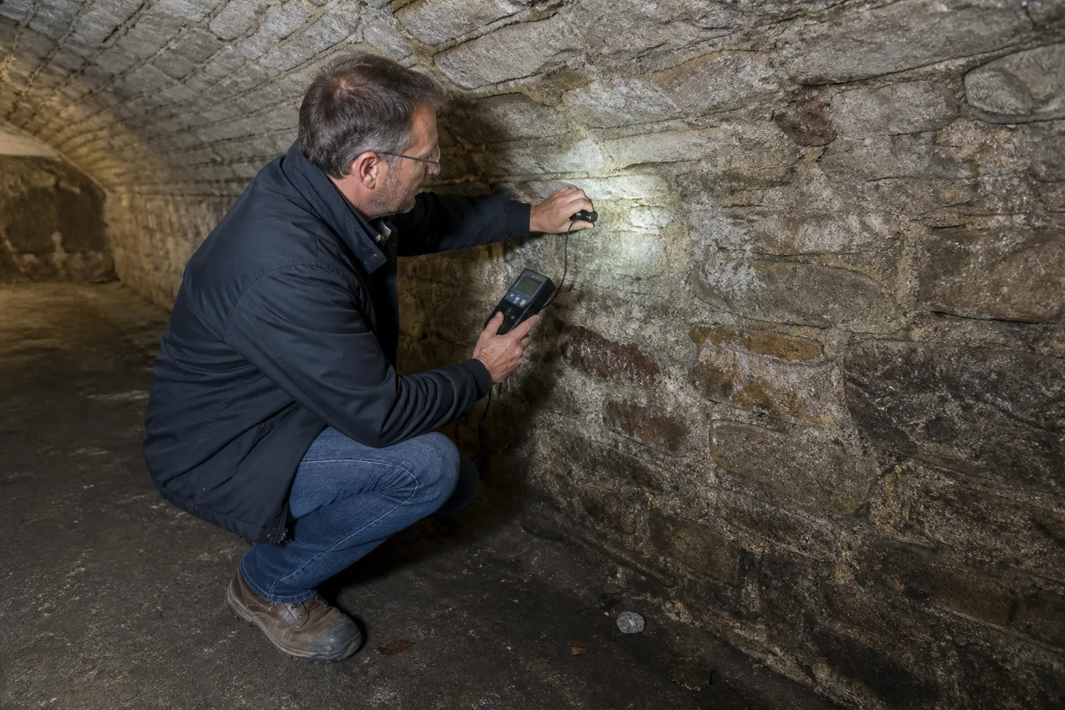 Expert mesurant l’humidité d’un mur de cave voûtée