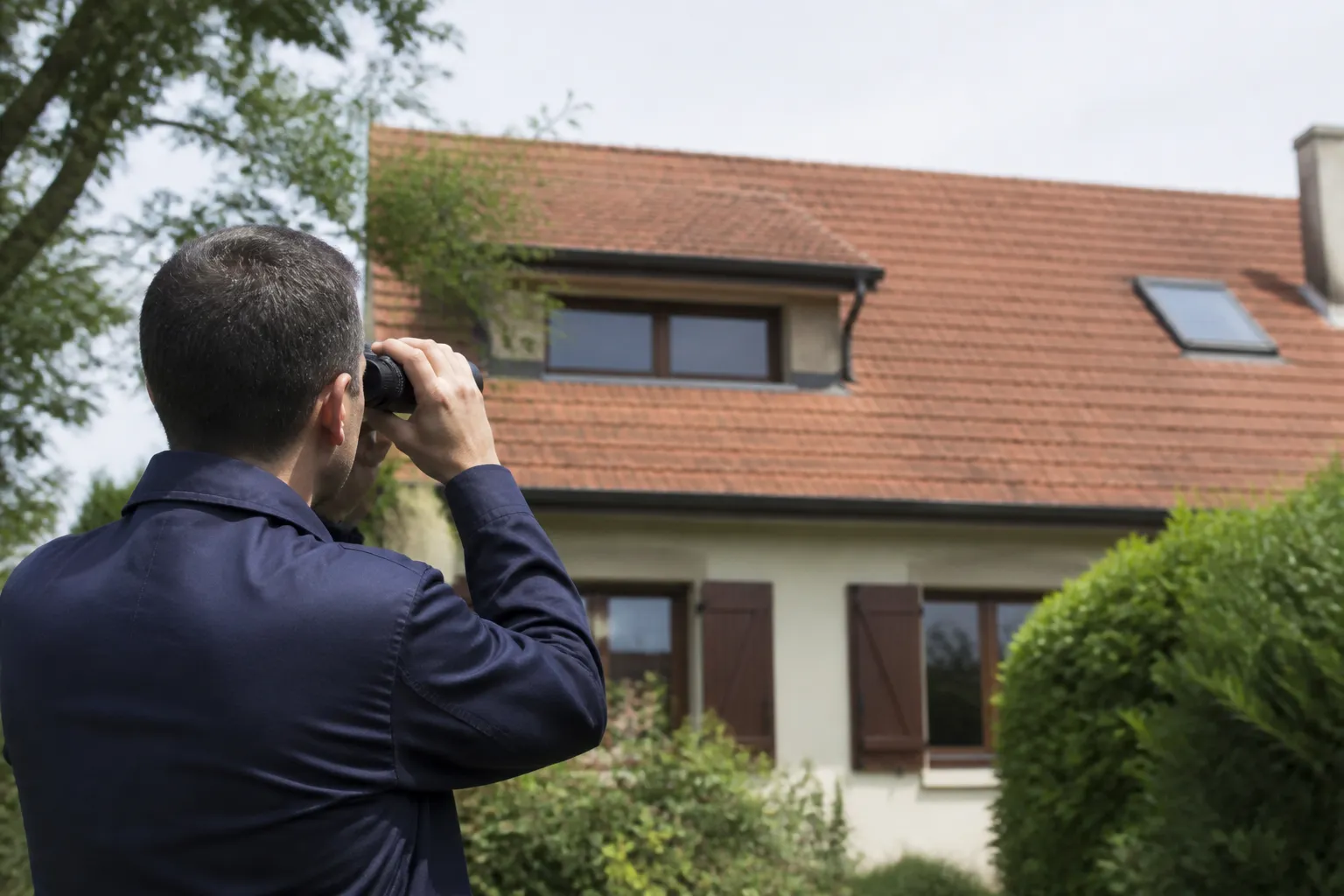 Expert observant une toiture depuis le jardin