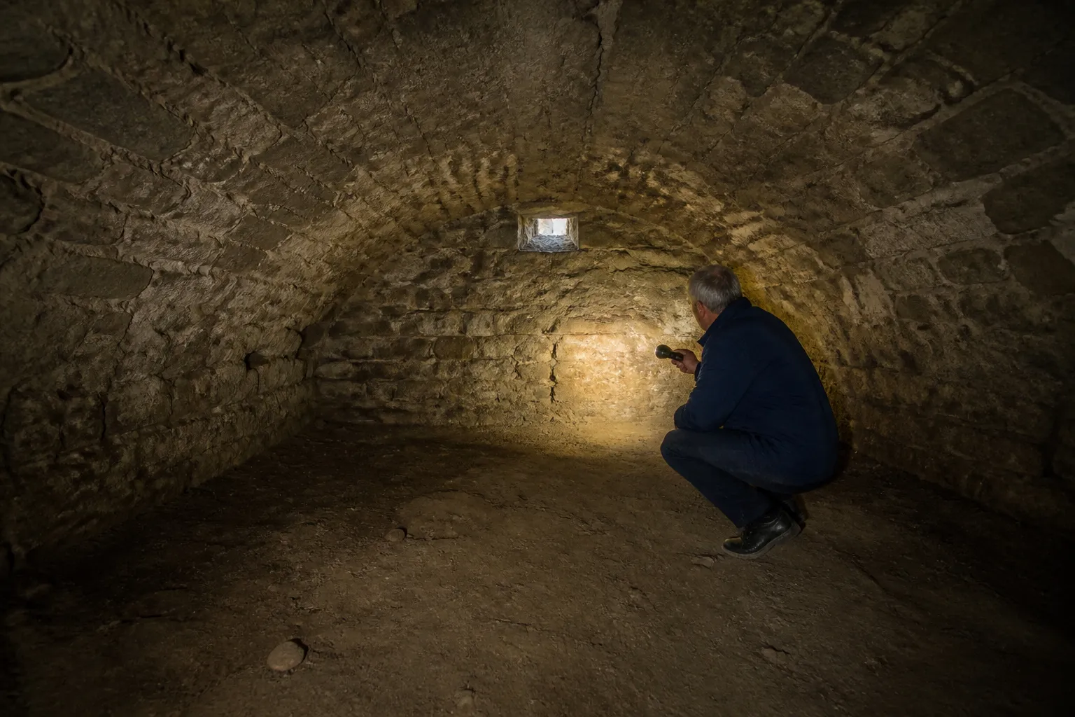Cave voûtée en pierre inspectée à la lampe