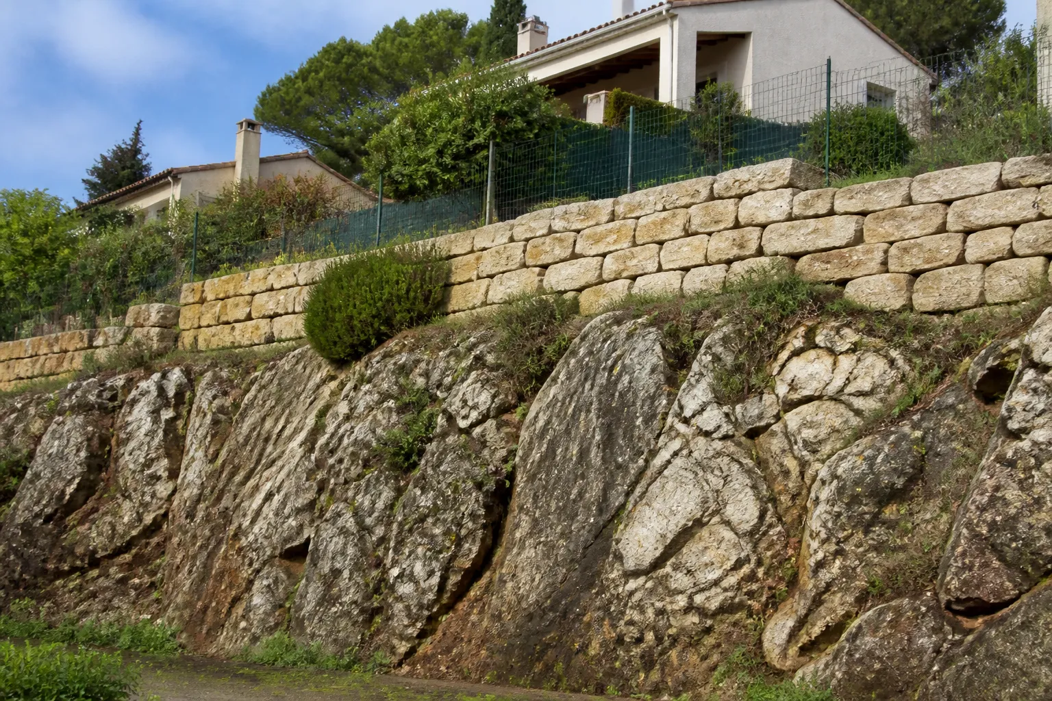 Talus rocheux avec mur de soutènement derrière des maisons