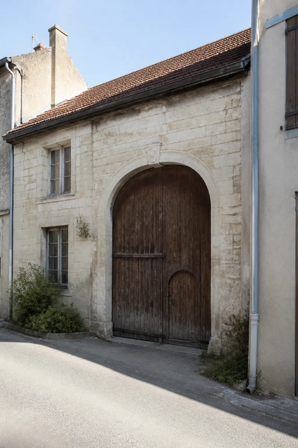 Maison de bourg en pierre avec porte cochère dans une petite ville de la Meuse