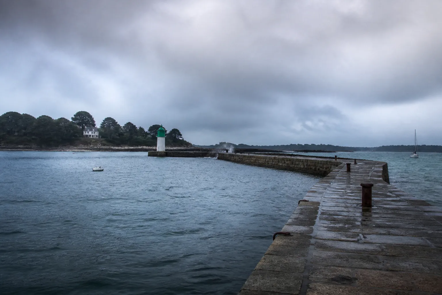 Quai et digue sous un ciel chargé dans une rade bretonne