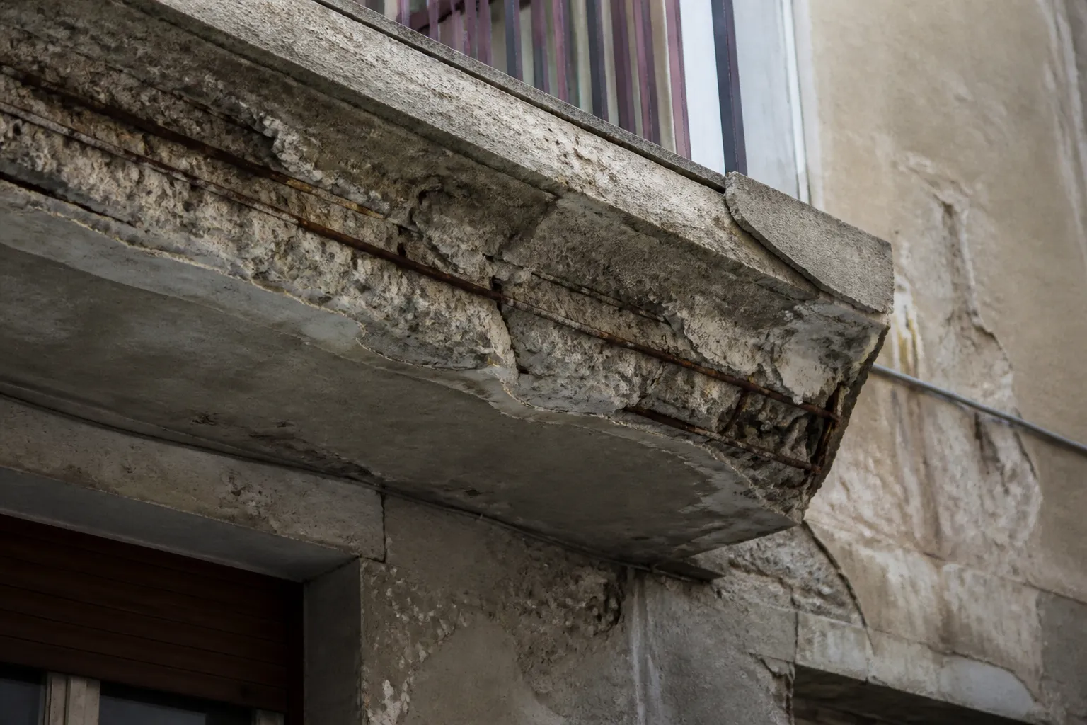 Façade d’immeuble en béton avec éclats et armatures visibles