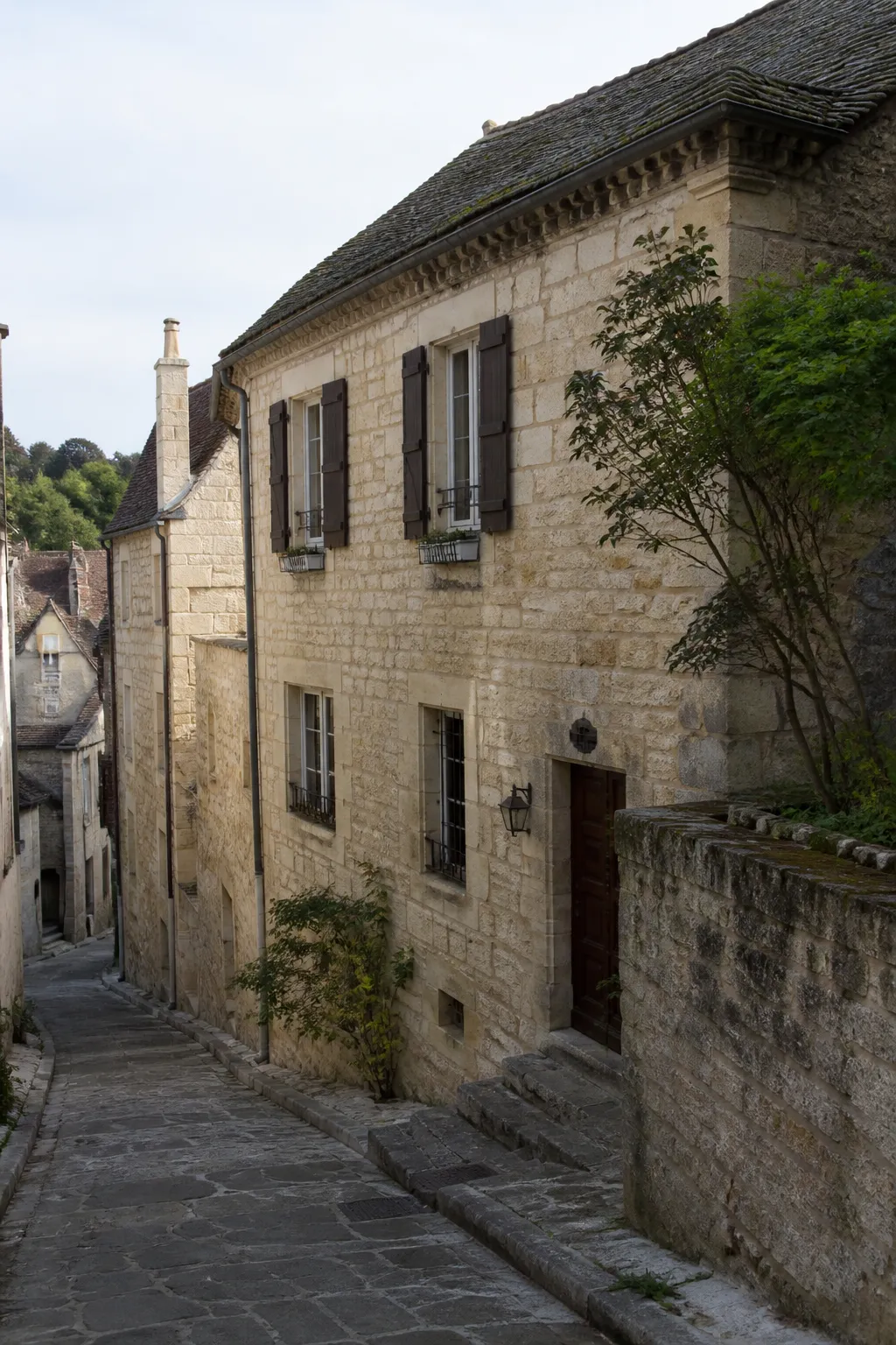 Maison de ville ancienne en pierre dans une rue en pente
