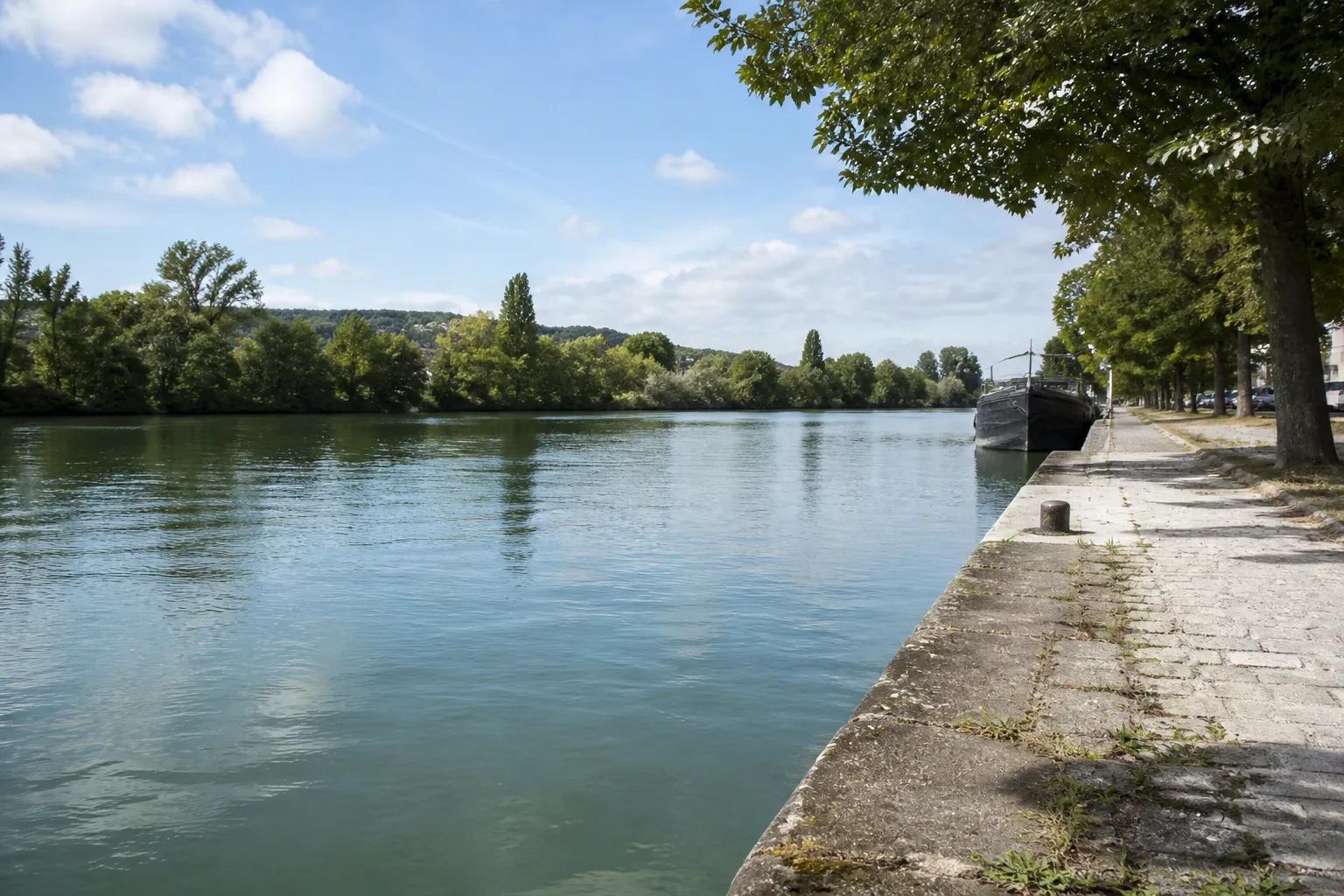 Large rivière navigable bordée de quais et d’arbres