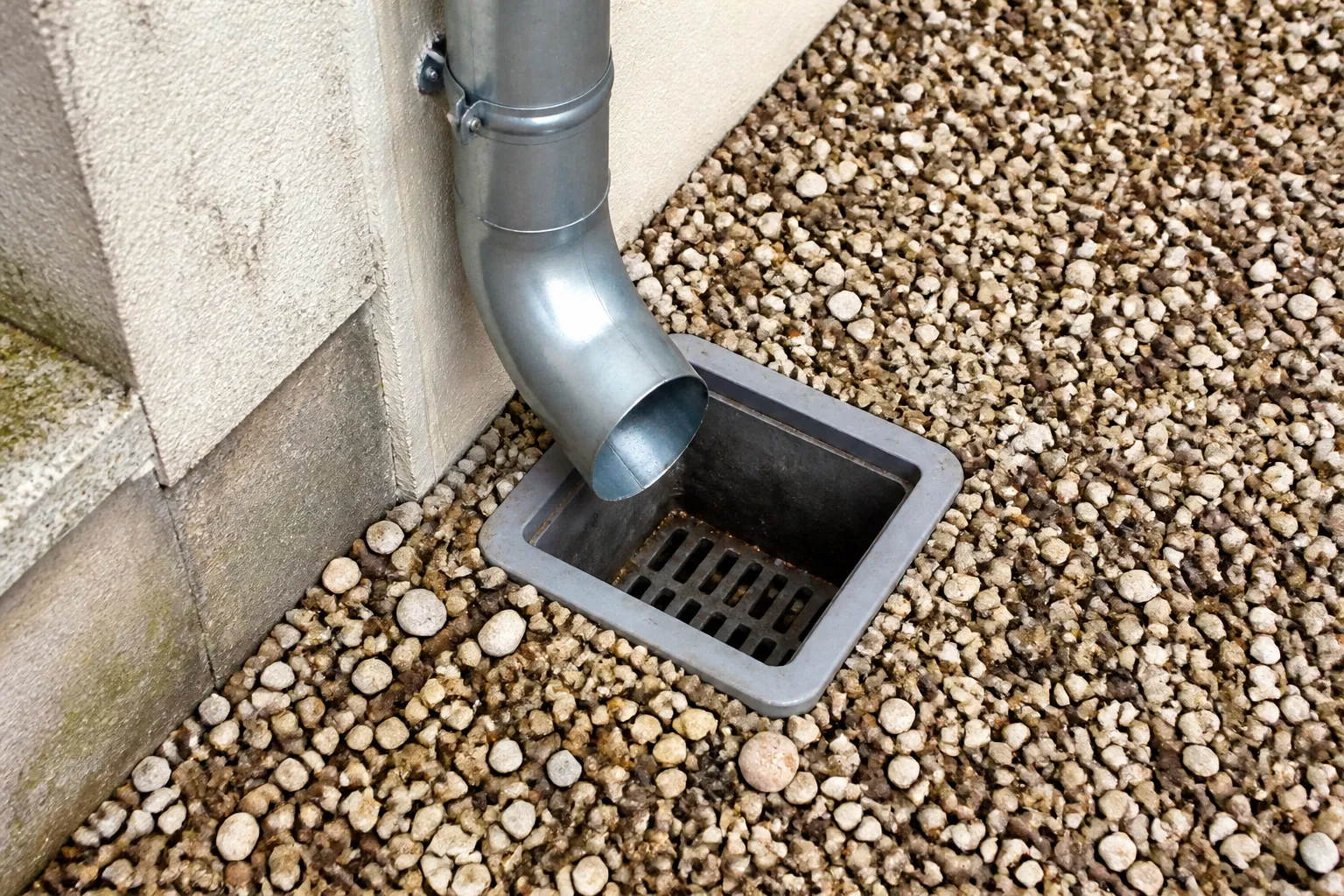 Descente d’eau pluviale et regard au pied d’une maison