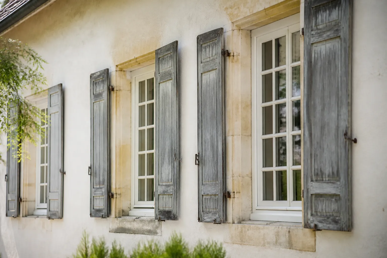 Fenêtres anciennes à petits carreaux et volets bois sur une façade enduite