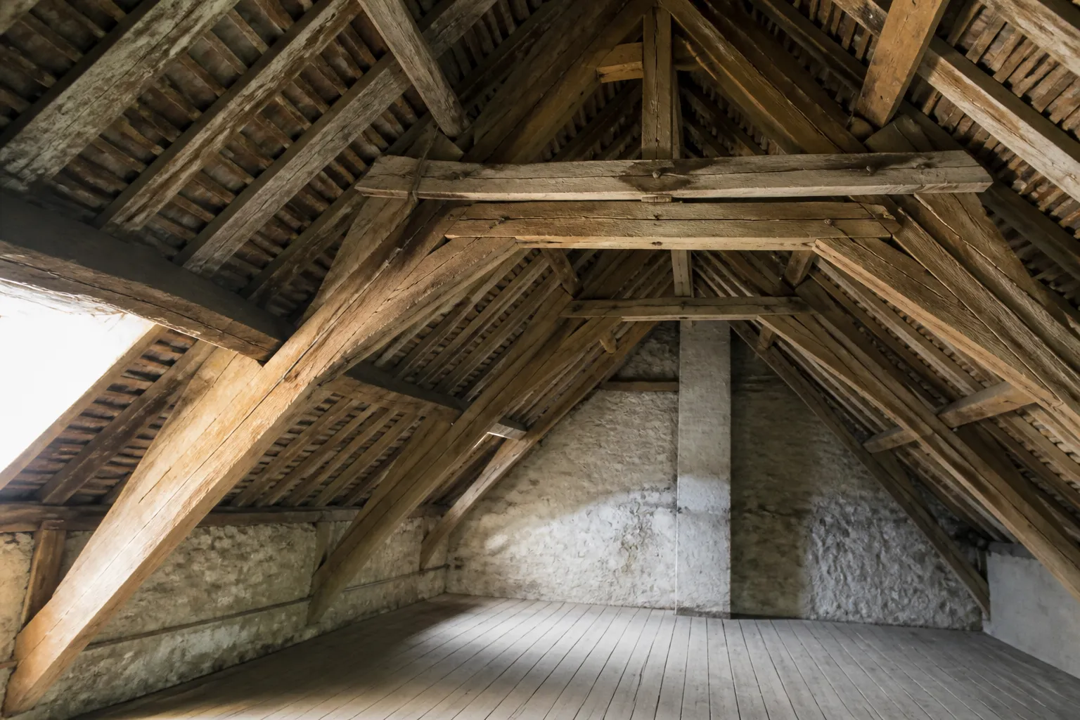 Charpente traditionnelle en bois vue depuis des combles