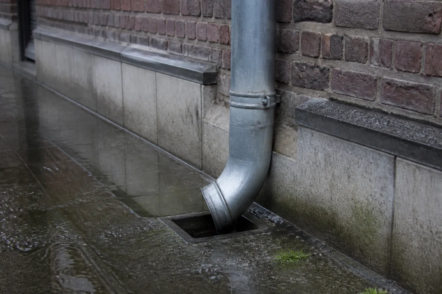 Gouttière et descente d’eaux pluviales au pied d’une façade