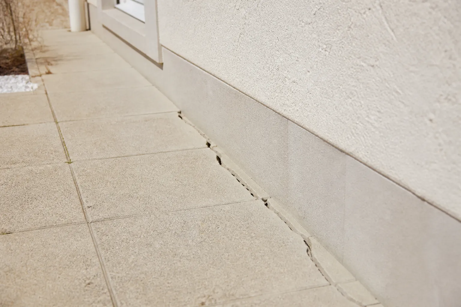 Dallage de terrasse fissuré le long d’une maison