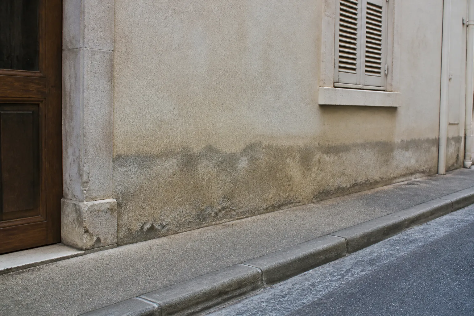 Trace horizontale d’humidité sur le bas d’une façade enduite