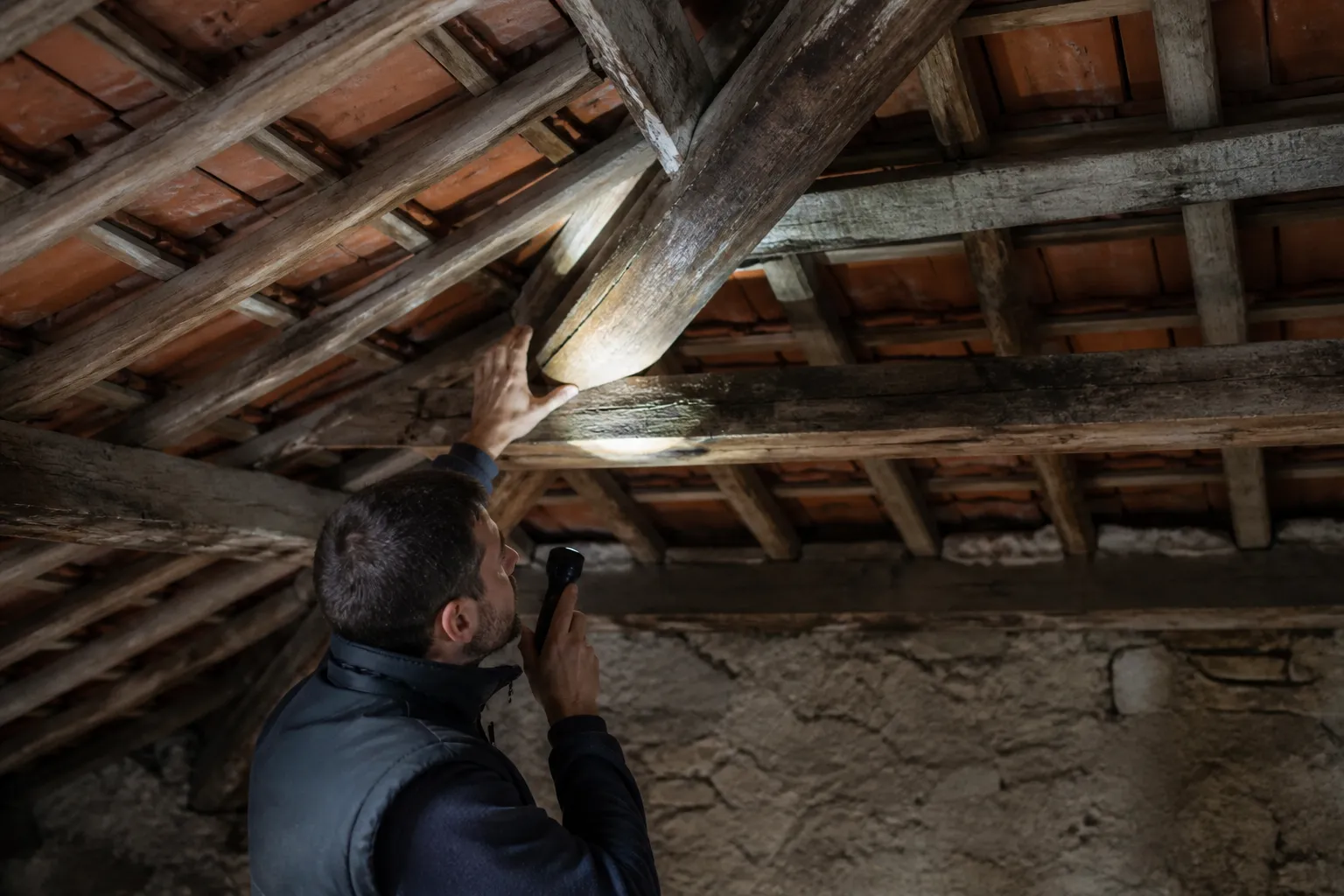 Expert examinant une charpente dans des combles