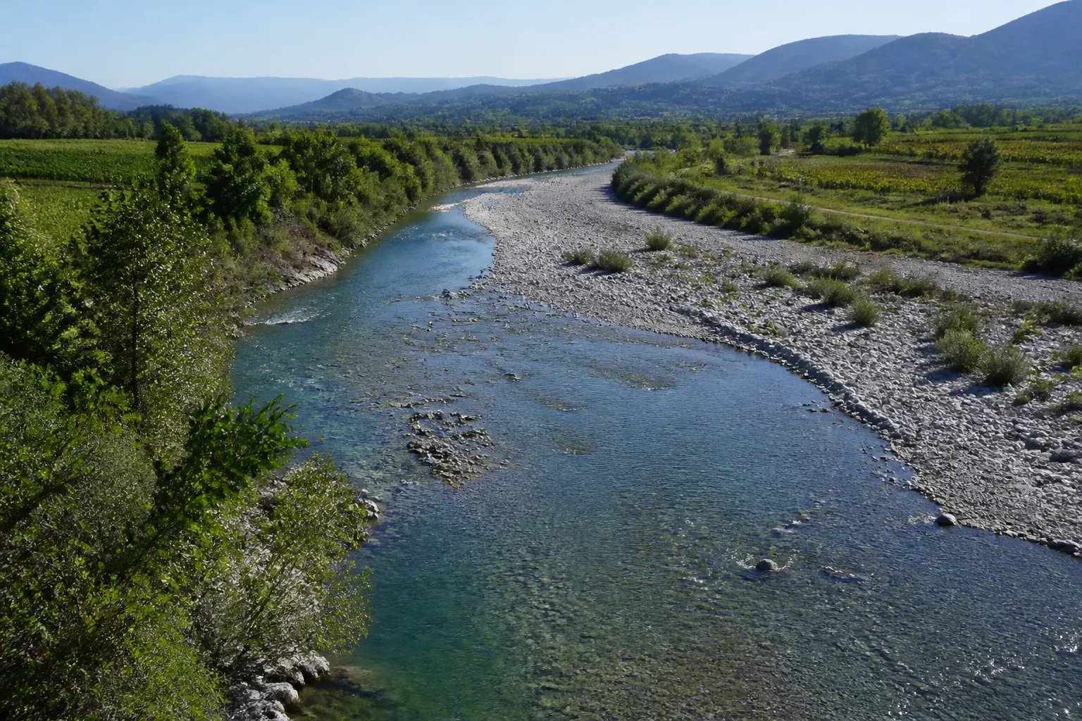 Rivière à lit large et galets en plaine agricole