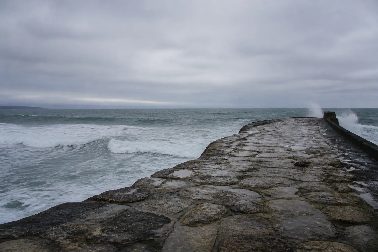 Digue en pierre face à l’océan par temps gris