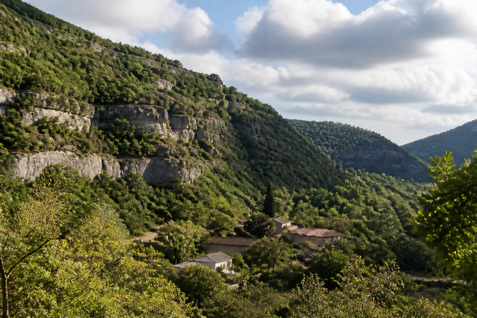 Vallon verdoyant avec coteau calcaire et maisons