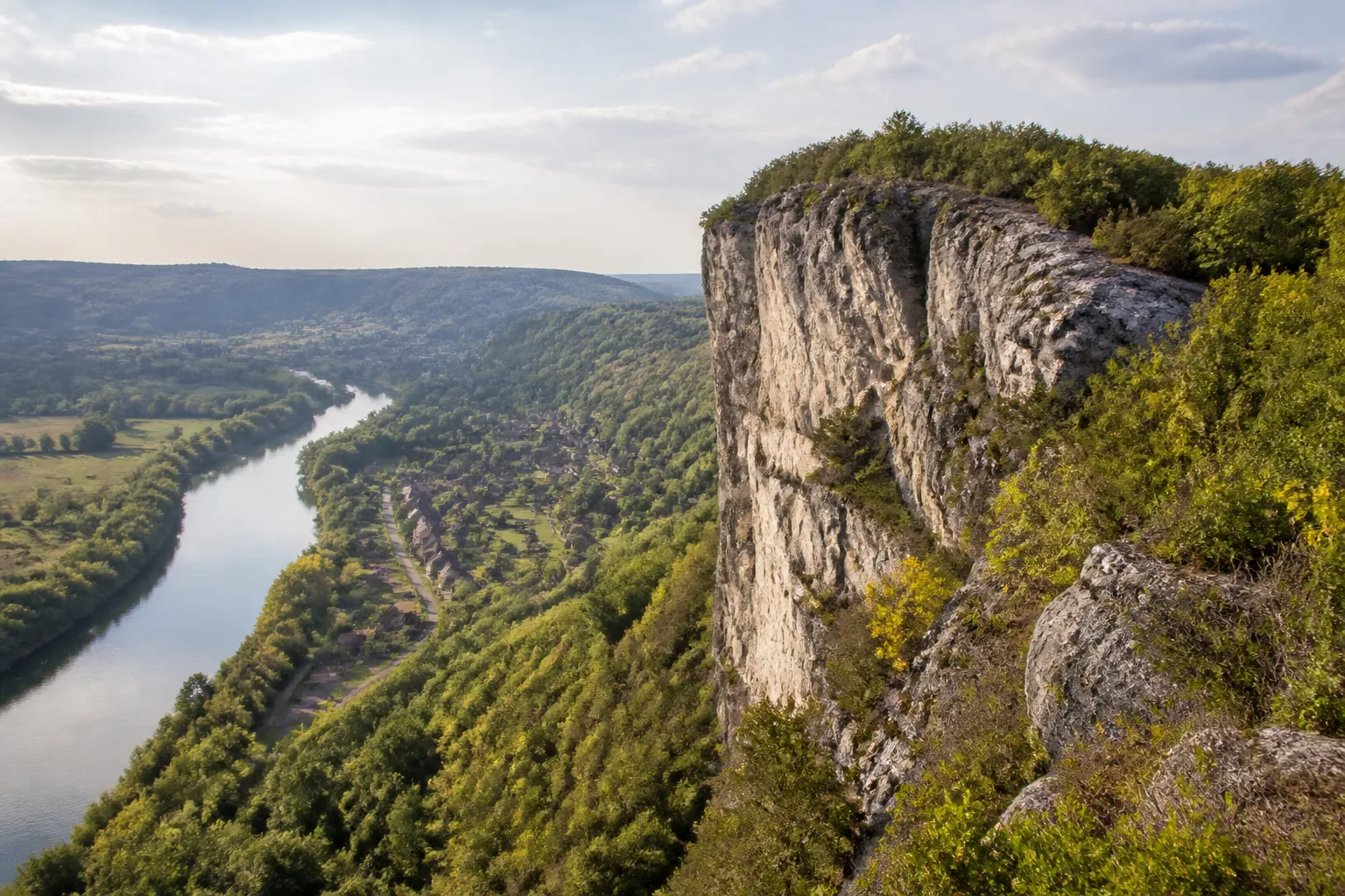 Falaise calcaire boisée dominant une vallée urbaine