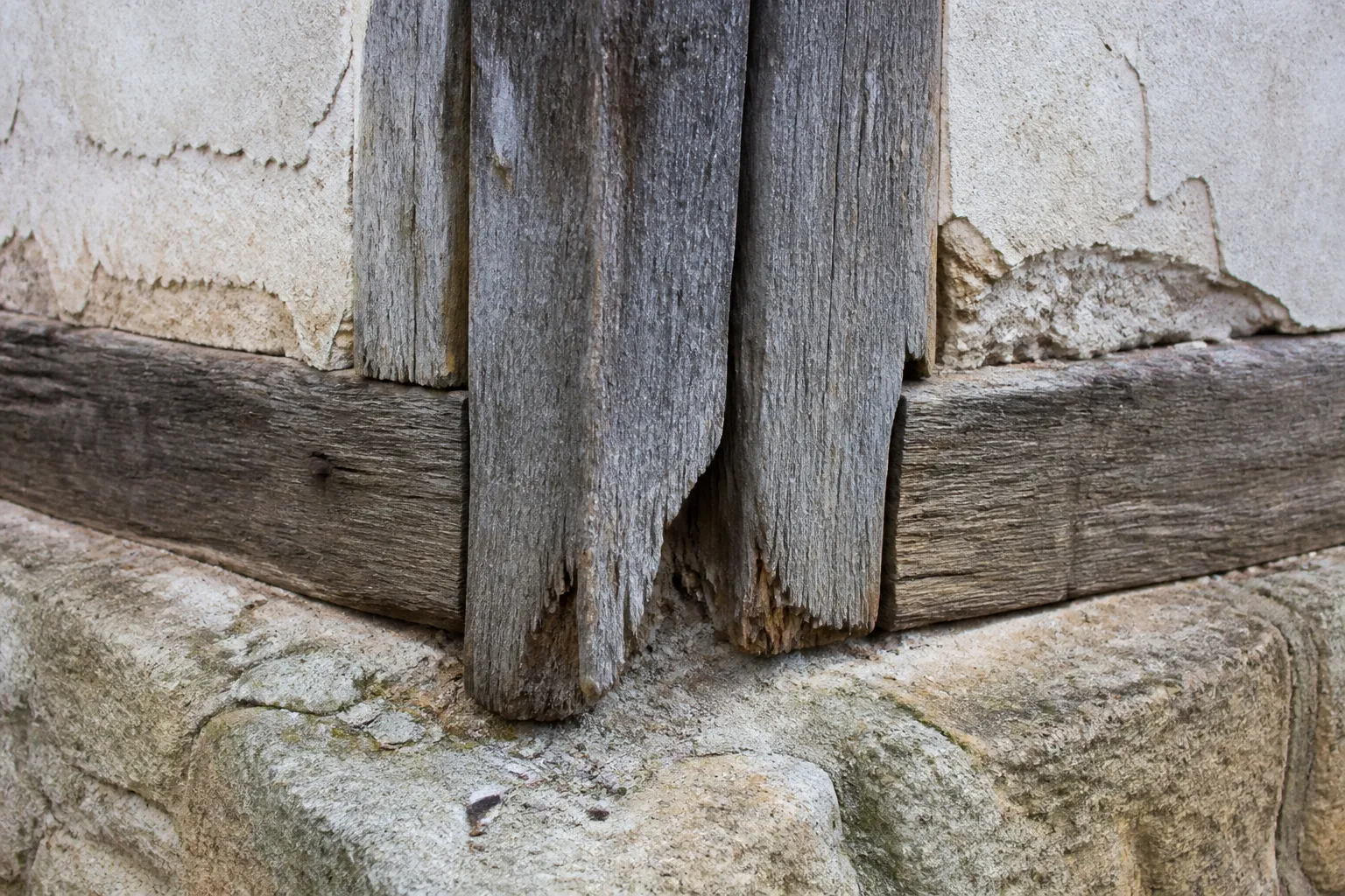 Poteau de pan de bois dégradé en pied de façade