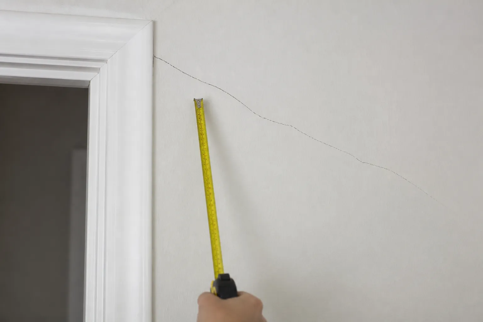 Fissure au-dessus d’une porte intérieure observée par un expert