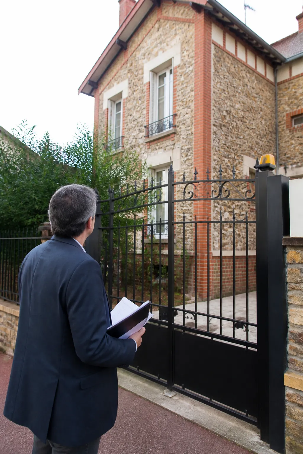 Expert en bâtiment devant un pavillon en banlieue sud de Paris