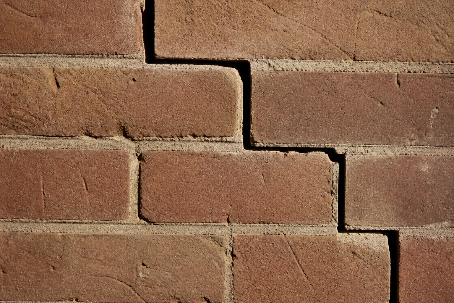 Mur de maison en briques avec fissure en escalier dans les joints
