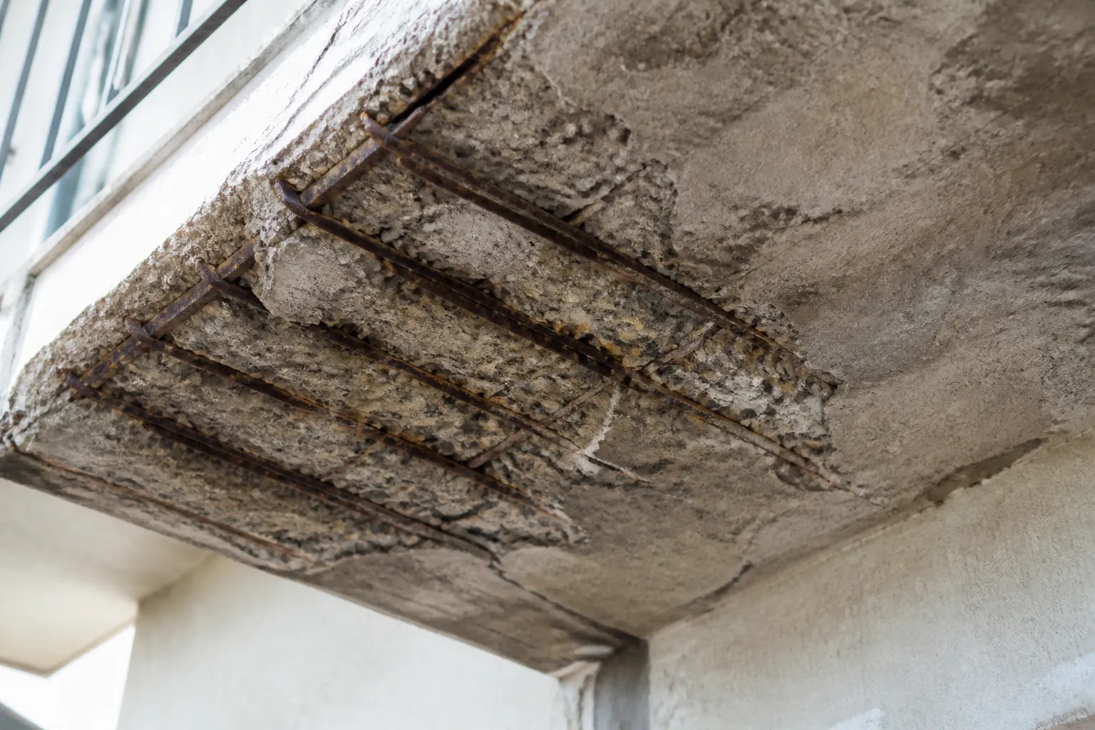 Sous-face de balcon en béton avec éclats et armatures visibles