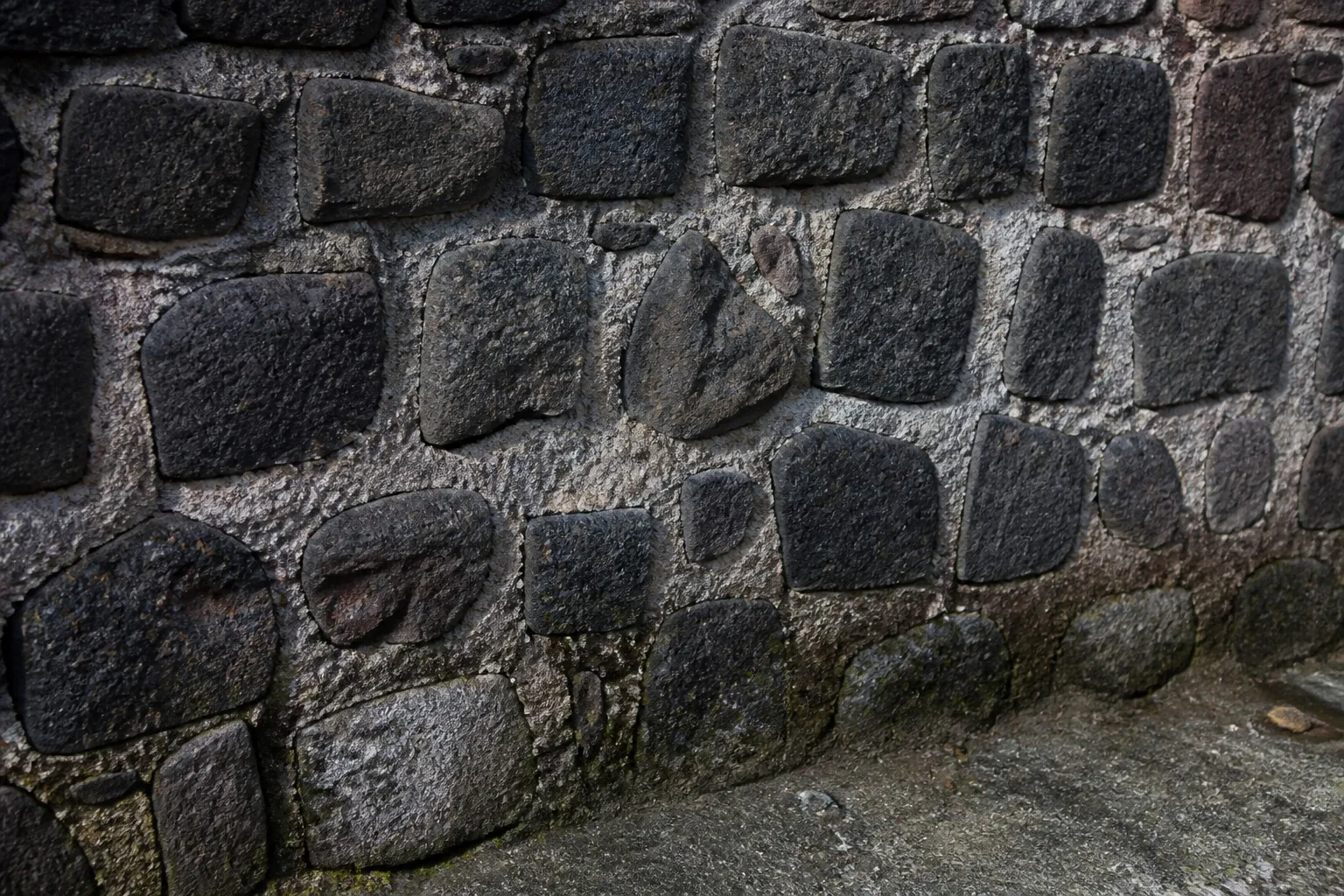 Mur en pierre volcanique sombre avec joints de mortier dégradés