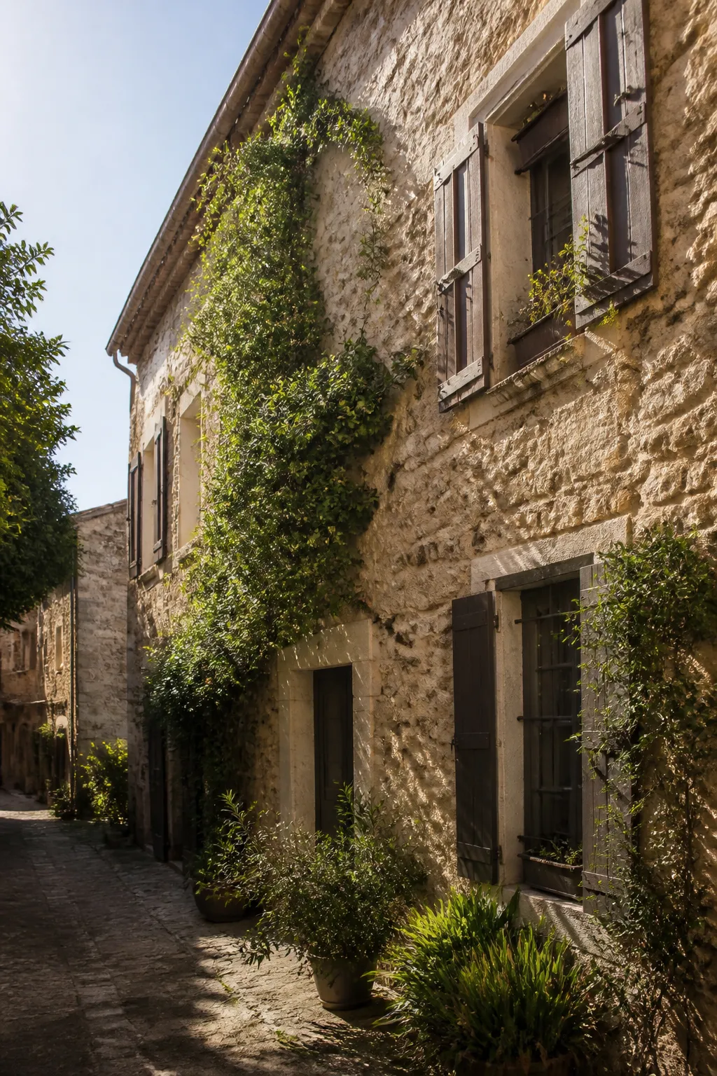 Maison ancienne aux murs de pierre et volets en bois dans une ruelle ensoleillée