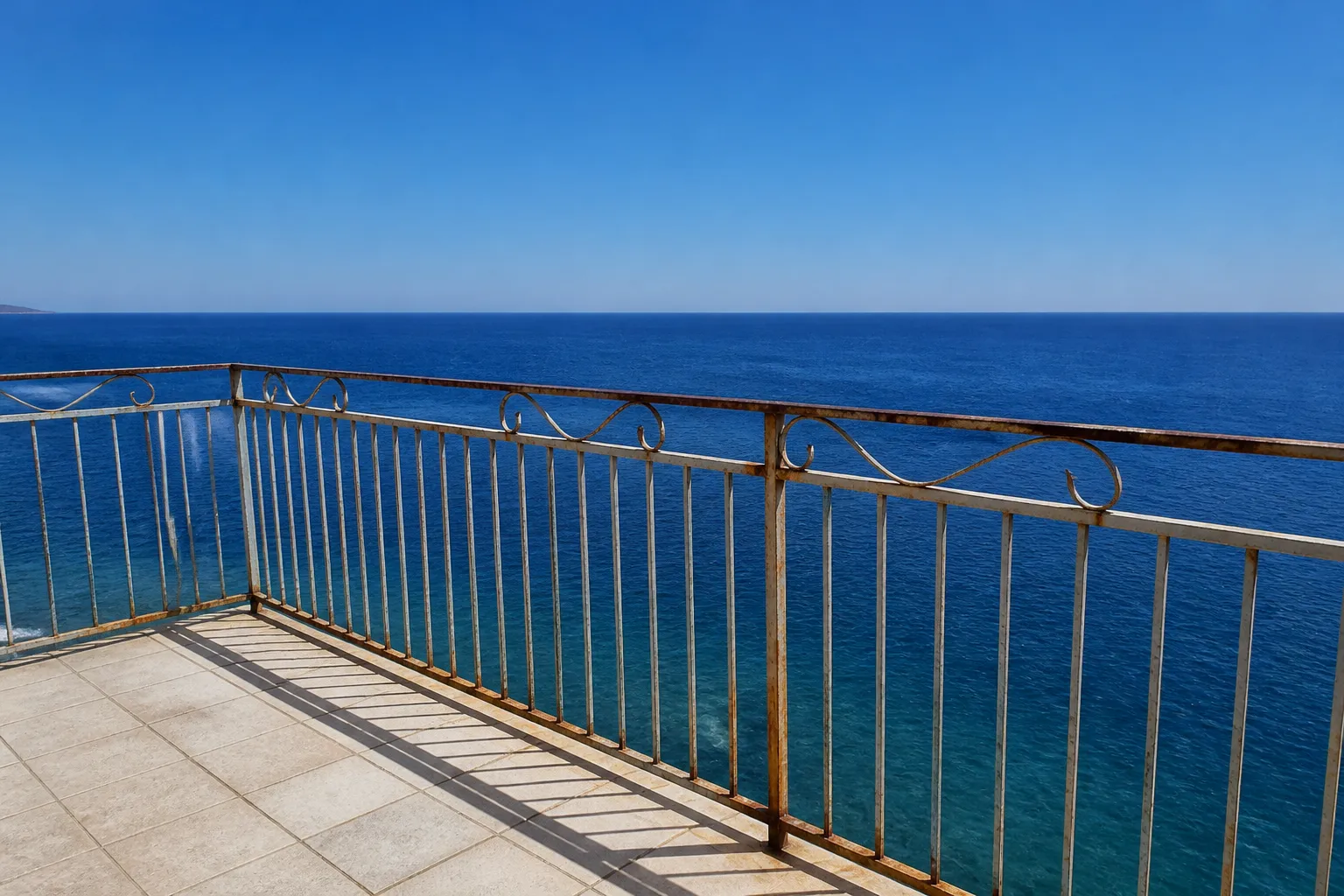 Garde-corps métallique corrodé sur une terrasse face à la mer