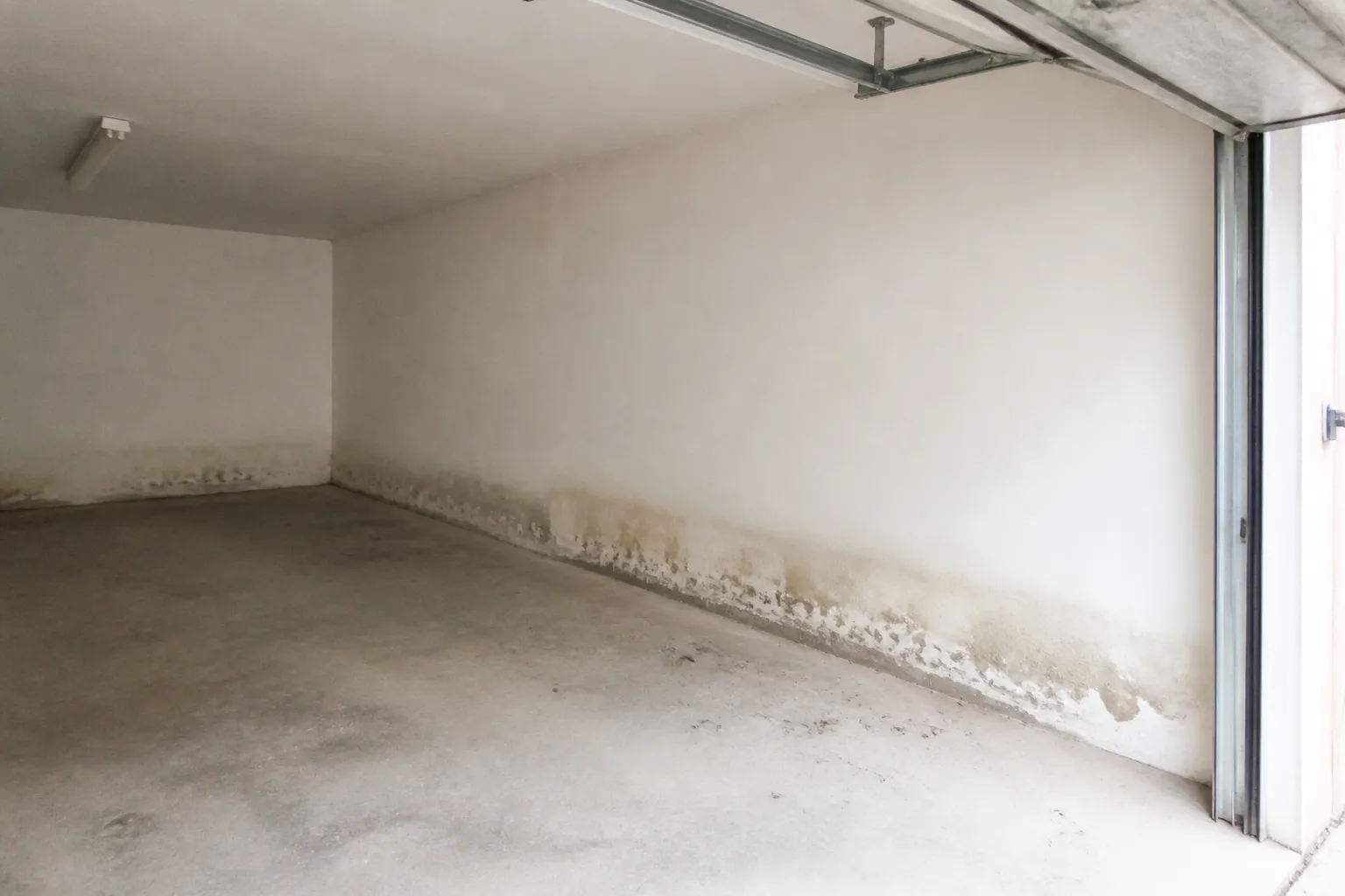 Garage en rez-de-chaussée avec marques d’humidité en bas des murs