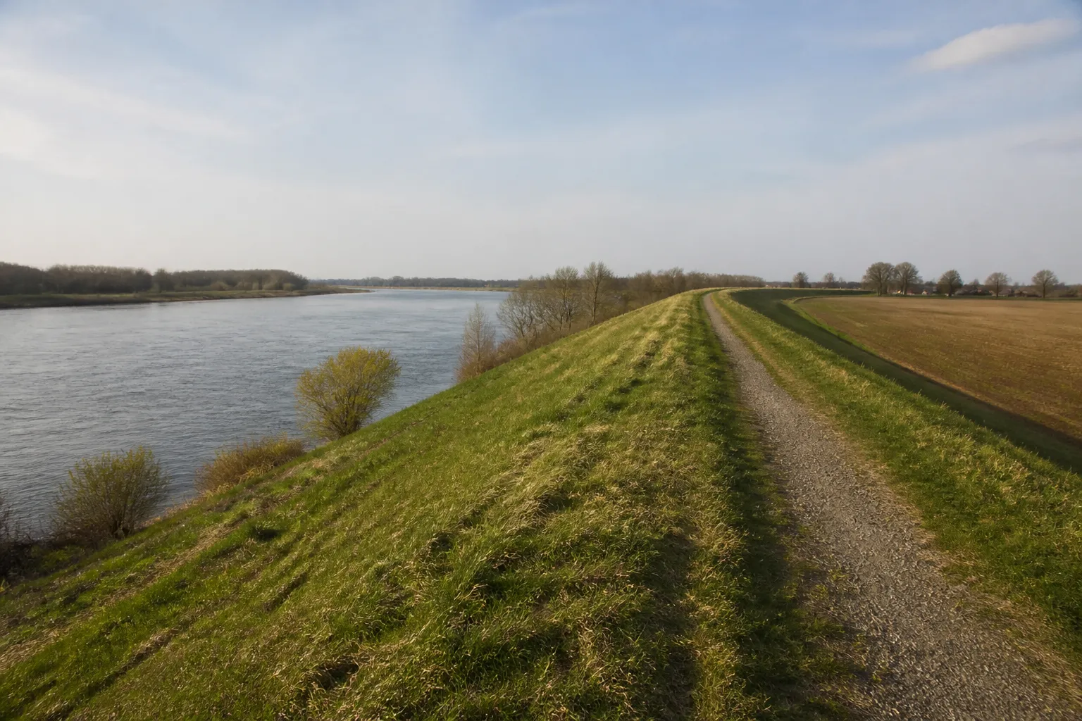 Digue enherbée séparant un fleuve d’une plaine agricole