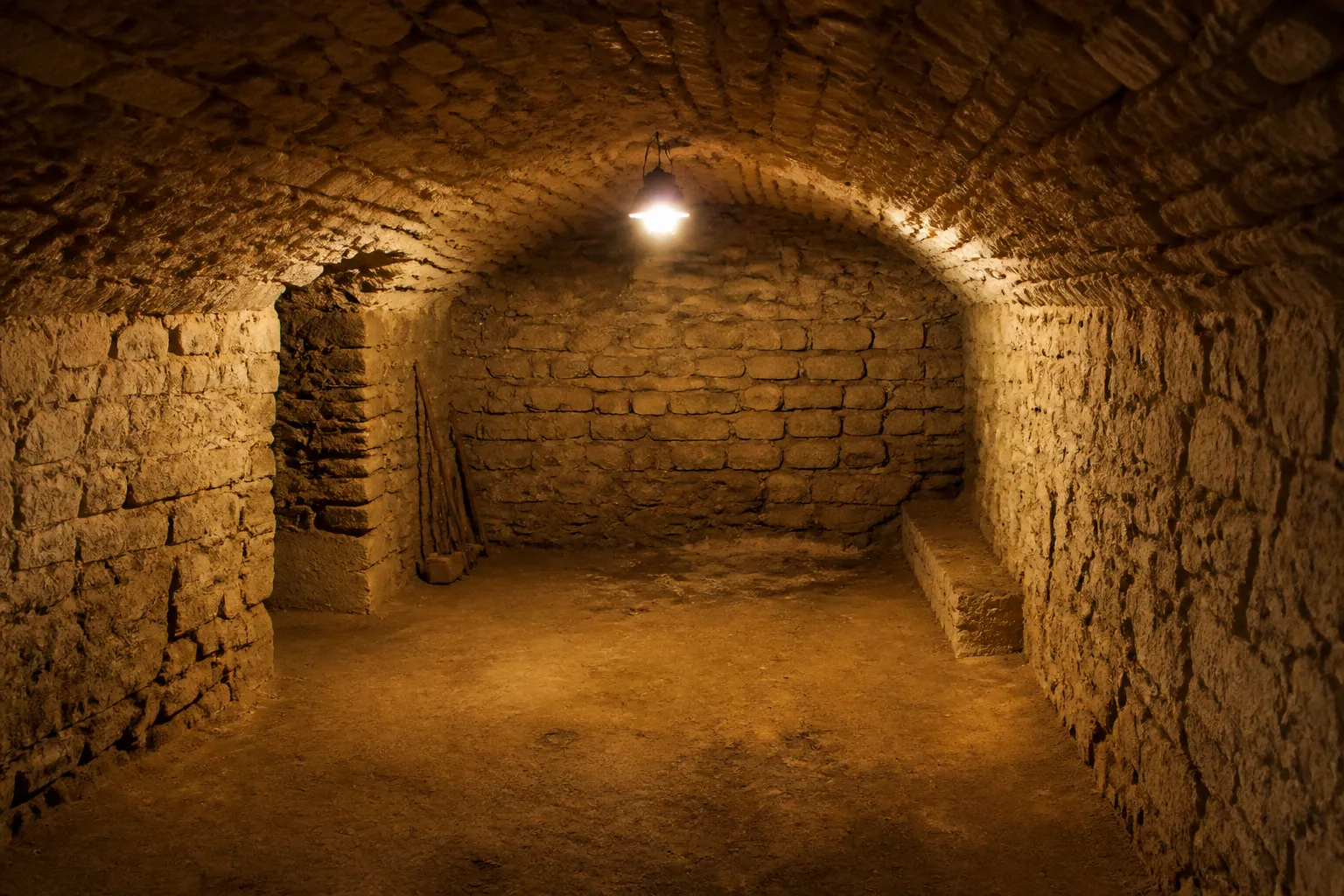 Cave voûtée en pierre d’une maison ancienne inspectée à la lampe