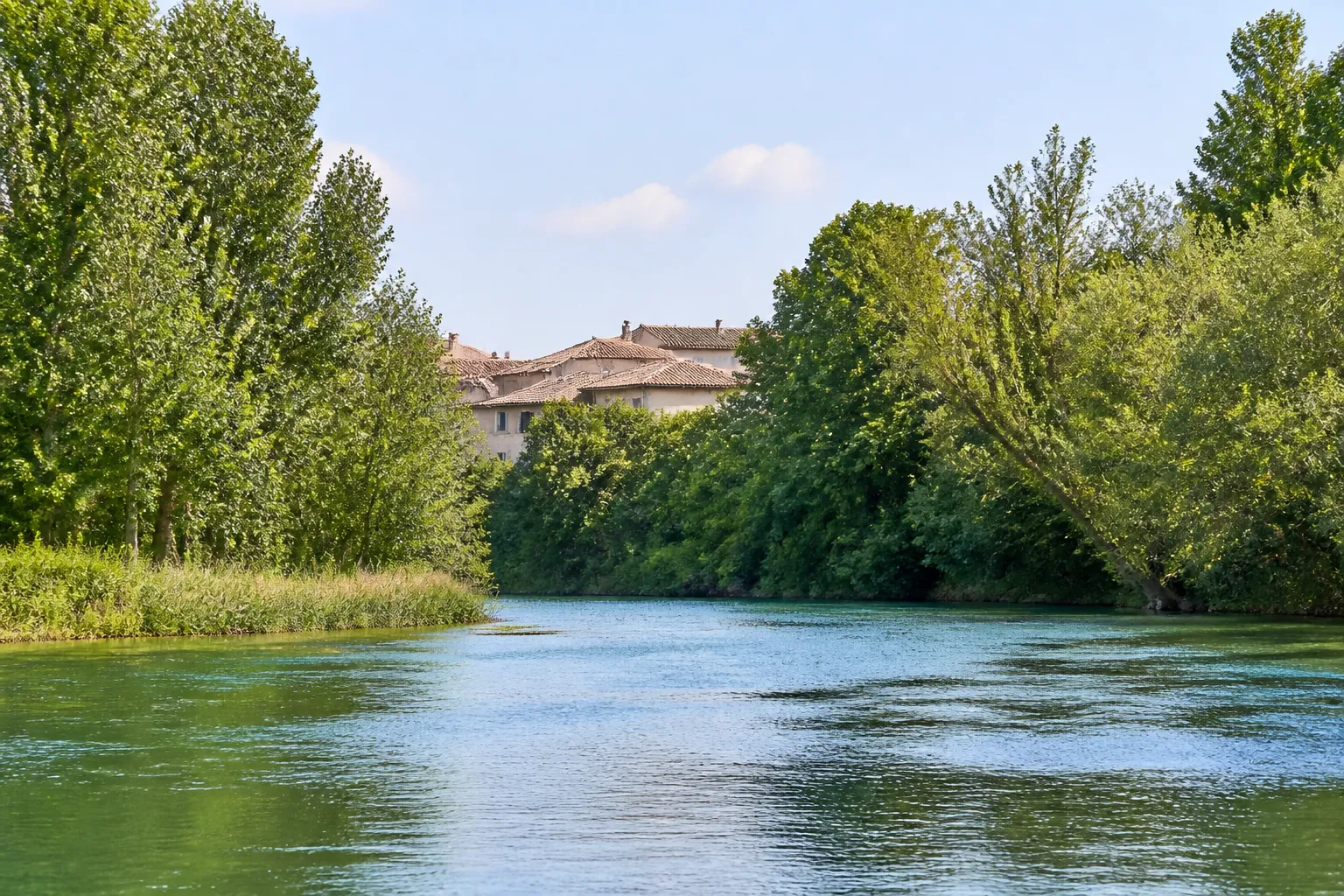 Berges arborées d’une rivière en plaine bordée de maisons