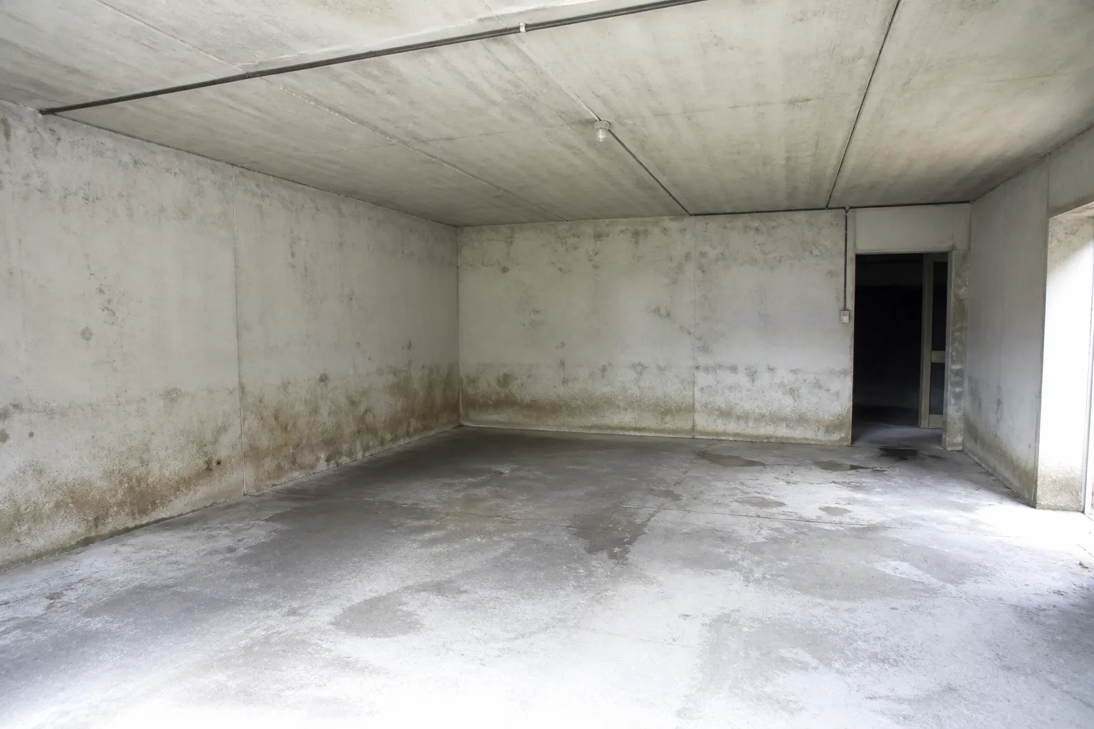 Garage en sous-sol avec traces d’eau anciennes en pied de mur