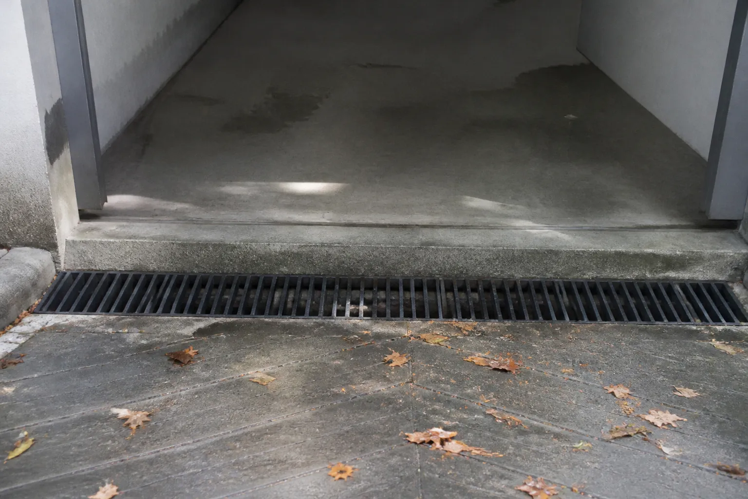 Grille d'évacuation des eaux pluviales devant un seuil de garage en contrebas