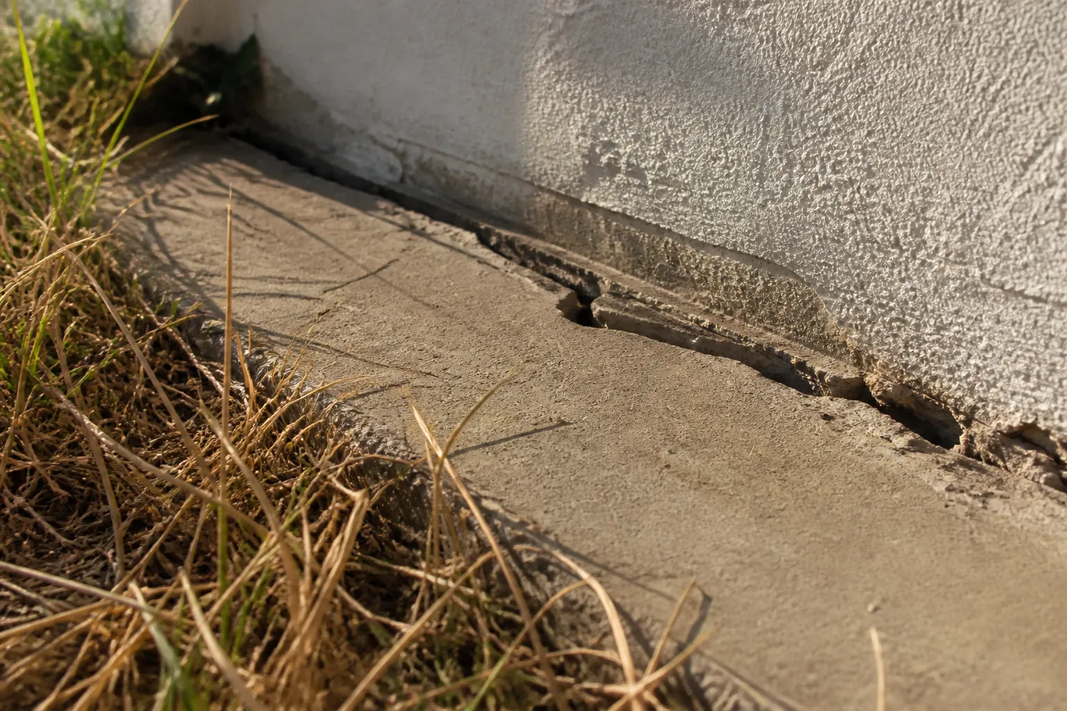 Fissure sur un dallage de terrasse le long d’une maison