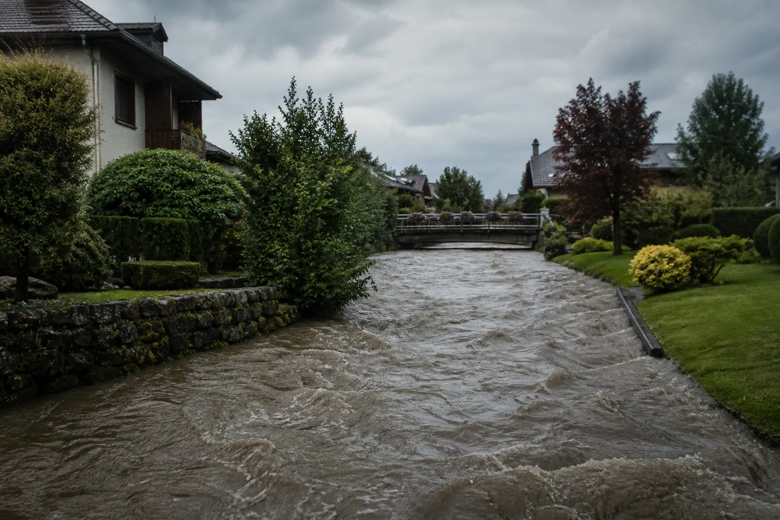 Petite rivière aux eaux hautes traversant un quartier résidentiel