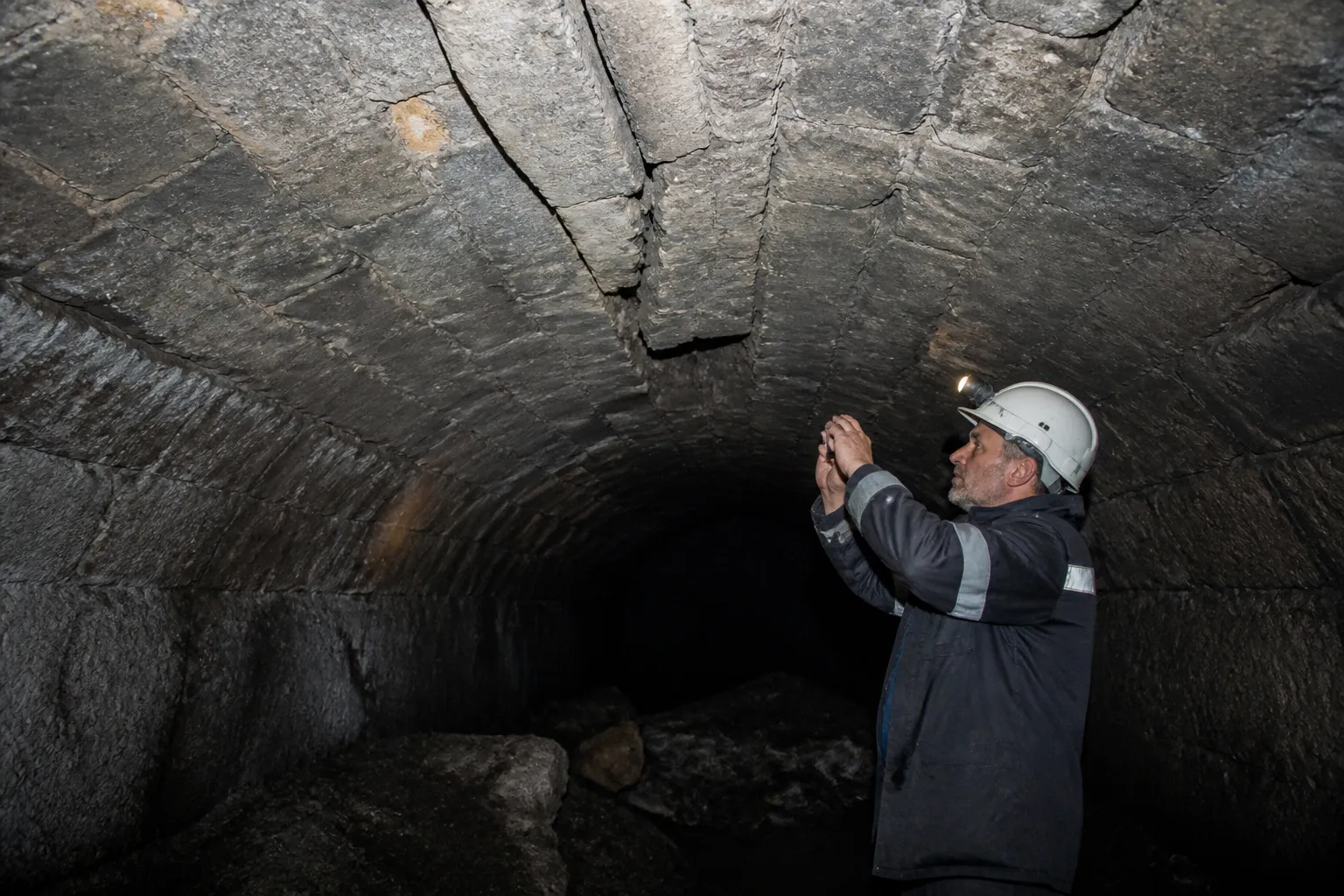 Cave voûtée en pierre sombre inspectée à la lampe frontale