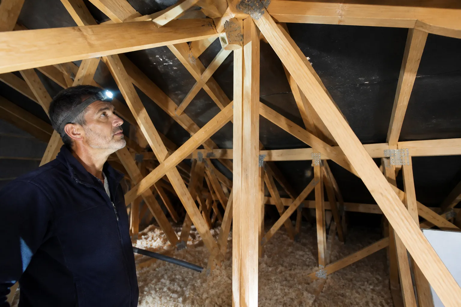 Expert en bâtiment inspectant des combles avec une lampe