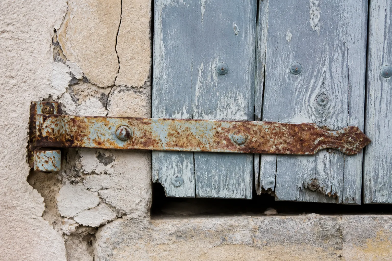 Ferrures de volet corrodées sur une façade exposée aux embruns