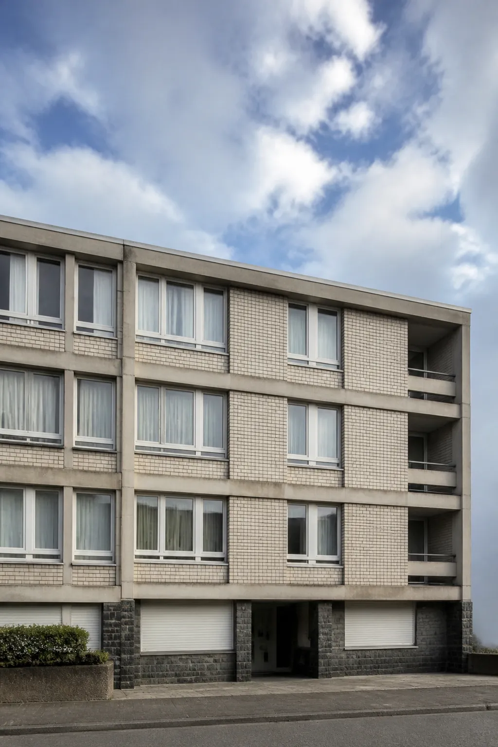 Immeuble d'habitation d'après-guerre en béton et brique sous un ciel du littoral