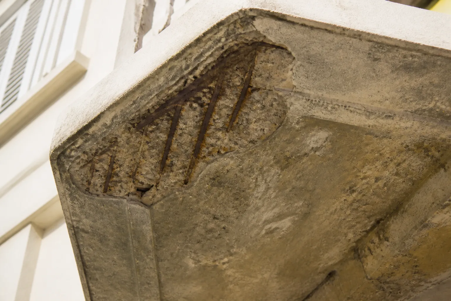 Balcon en béton avec éclat et armature apparente en sous-face